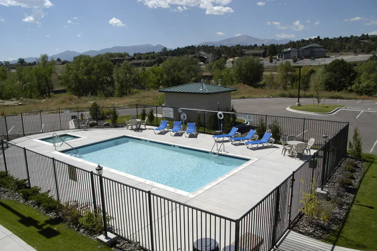 An inviting exterior view of a shared BBQ area adjacent to the swimming pool, complete with lounge chairs and festive landscaping. The space is set up for social gatherings, with cues for grilling and outdoor dining.