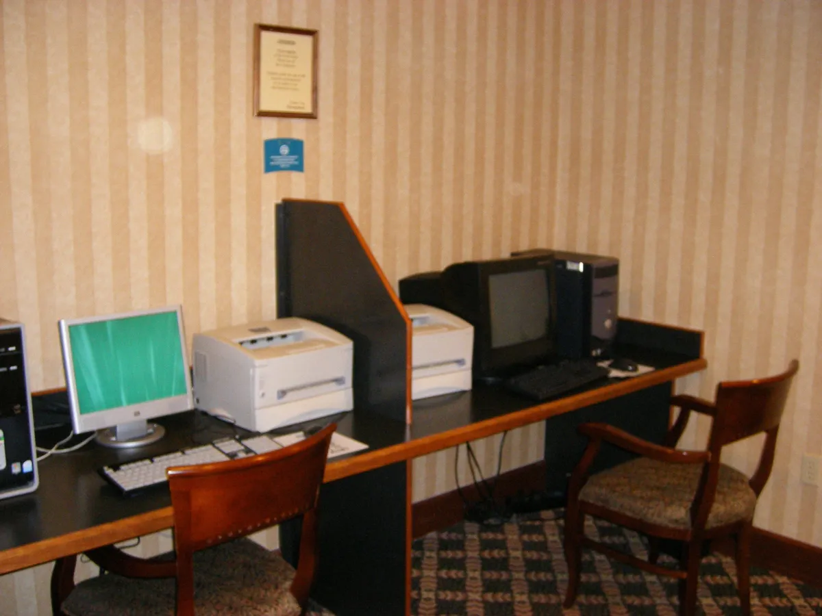 A practical business center with computers, printers, and comfortable seating is shown, designed for productivity and convenience. The scene is tidy and functional, ideal for guests needing to catch up on work or print important documents.