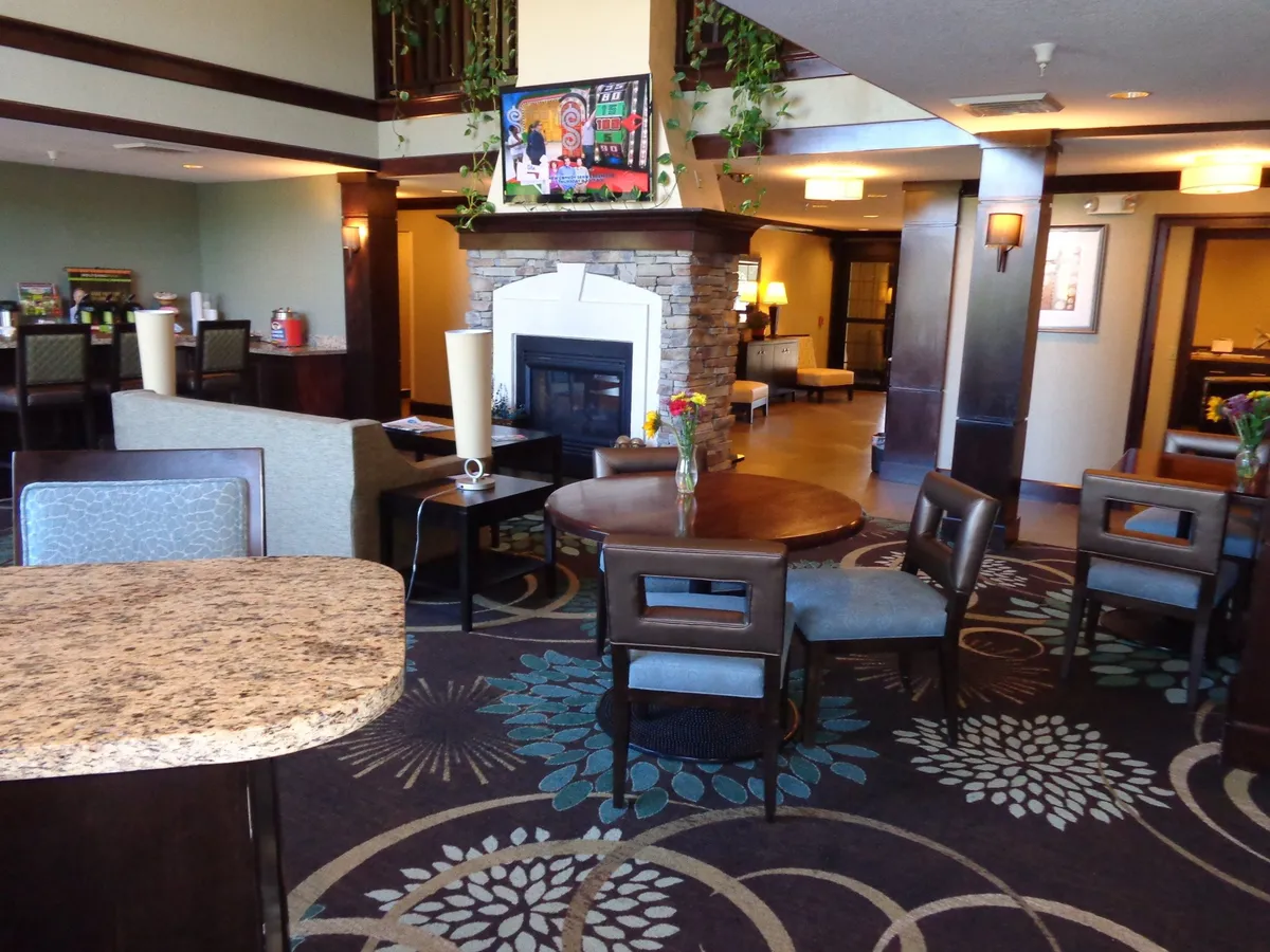 A welcoming living room scene with a fireplace, a dining table set for conversation or meals, tasteful wall art, and fresh floral arrangements. The space exudes warmth and comfort, ideal for relaxing, socializing, or enjoying a casual meal.